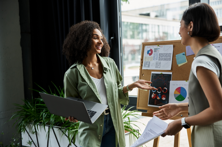 two women engaged in a professional discussion, standing in an office space discussing what is push and pull marketing